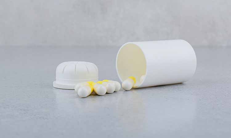 pote de medicamento branco com capsulas brancas e amarelas