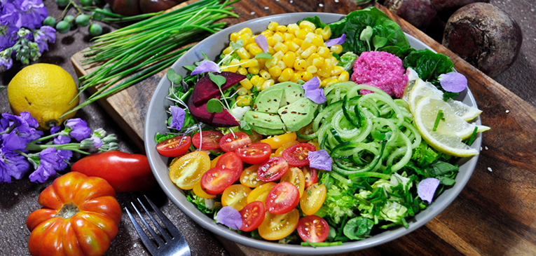imagem de um prato com diversas frutas e legumas dentro com uma colher ao lado