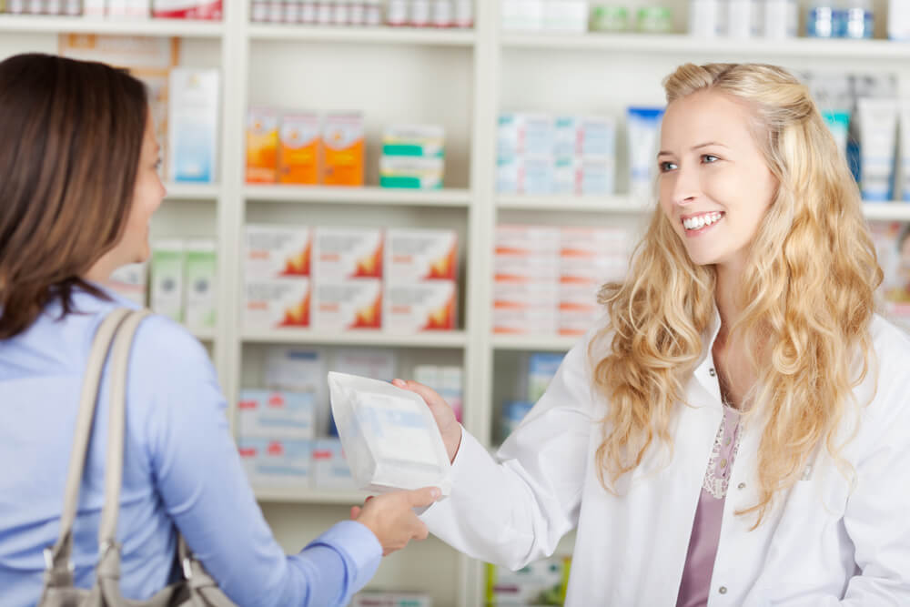 duas mulheres em uma farmácia de manipulação com um pacote na mão