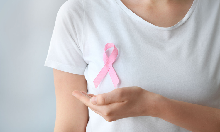 mulher com blusa branca e simbolo do cancer de mama em rosa