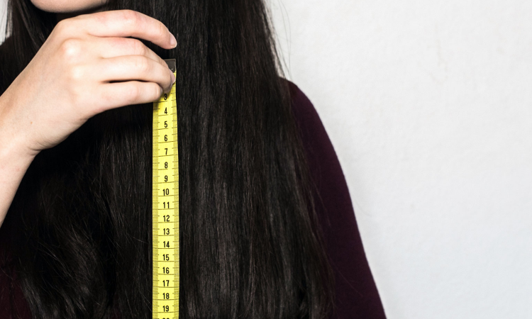 mulher de cabelos pretos longos com uma fita métrica perto do cabelo