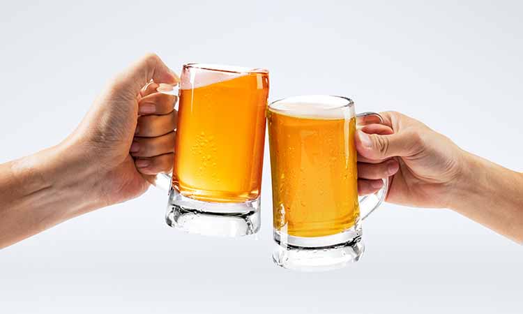 Duas mãos segurando dois copos de cerveja